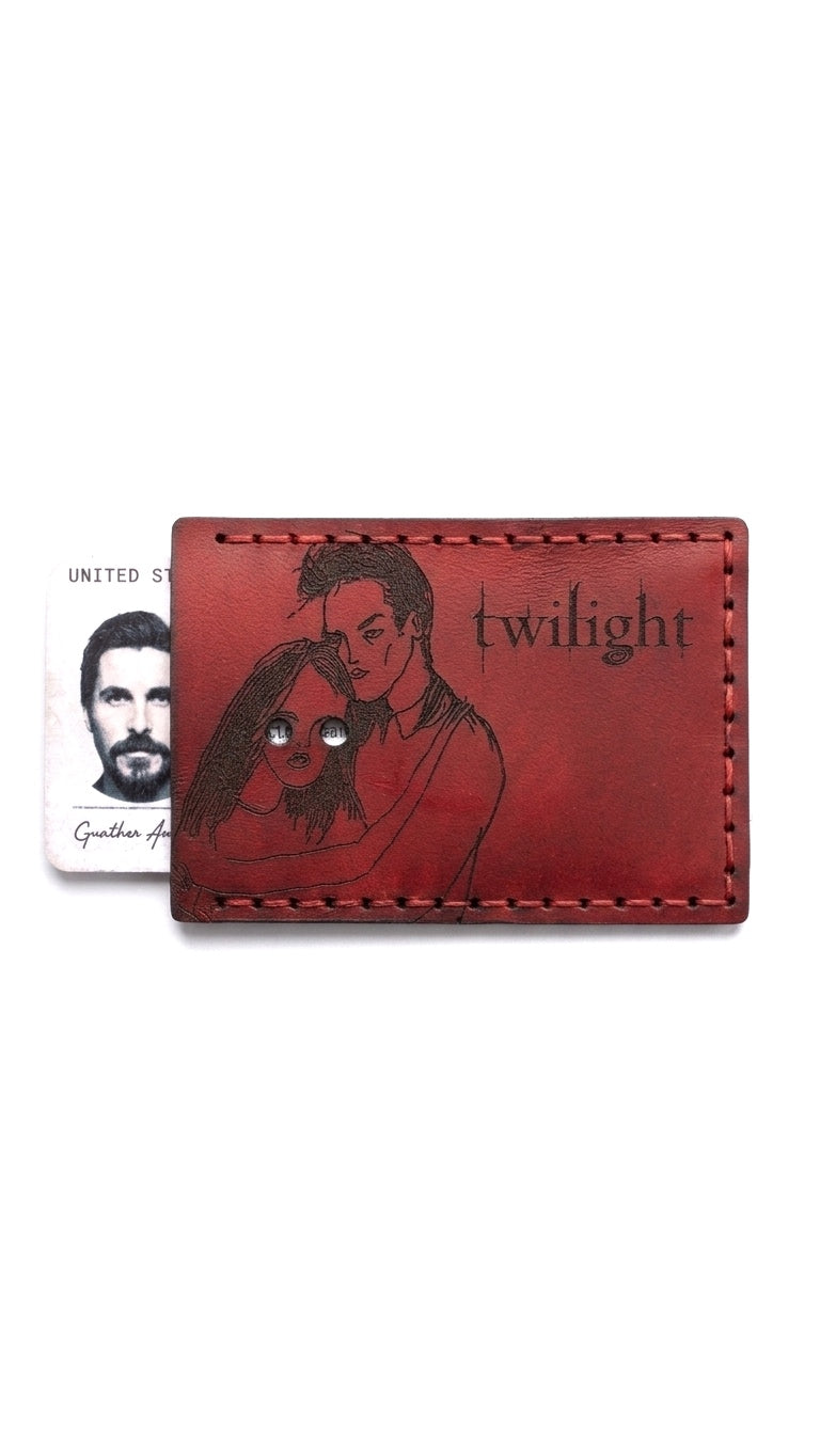 Handcrafted vibrant red leather ID card holder with an engraved Twilight movie silhouette of Edward and Bella. A custom circular cutout is positioned over the character's eyes to reveal the owner's ID photo. Features rustic black hand-stitching on premium genuine leather
