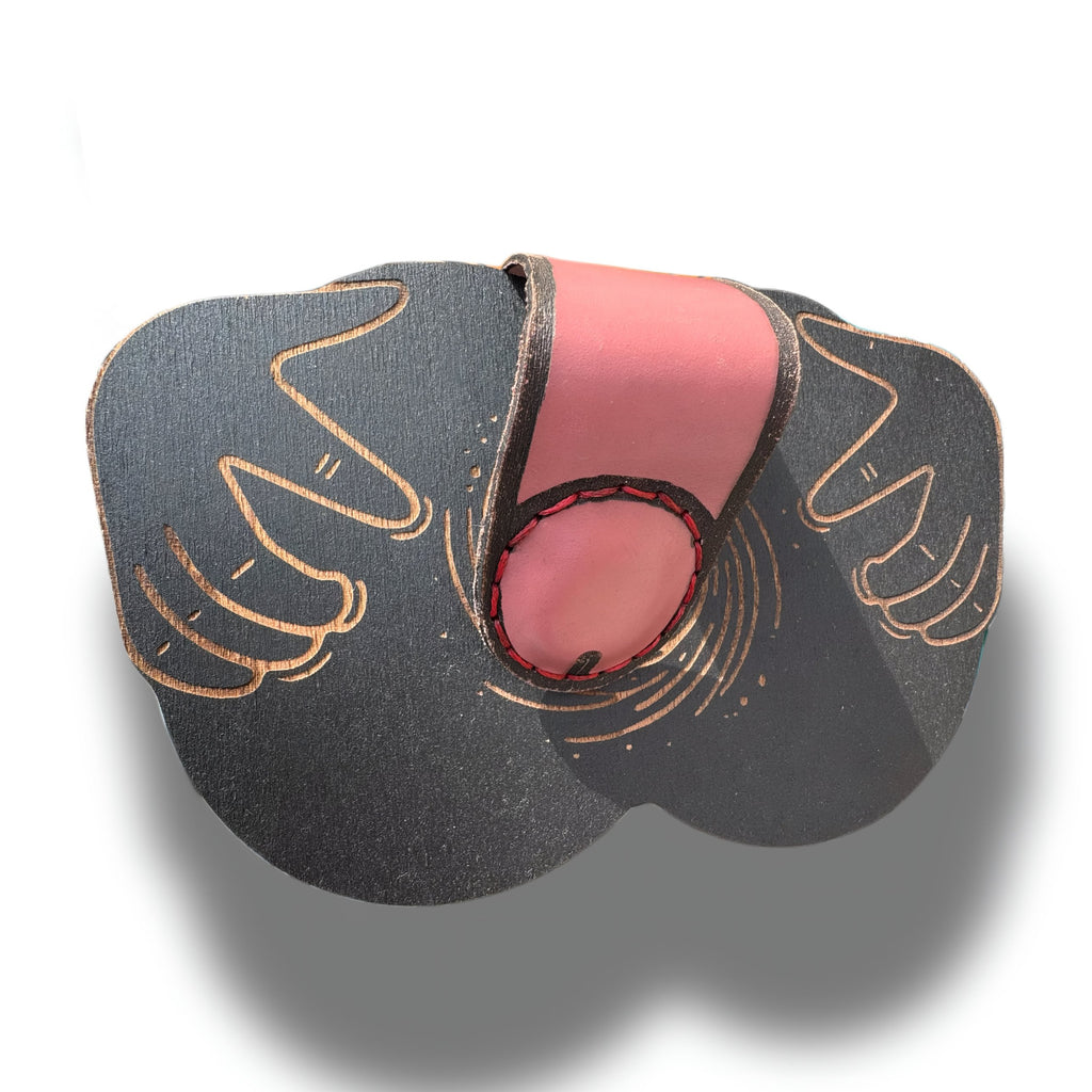 Engraved hands and black hole swirl on box lid, pink leather strap draped across