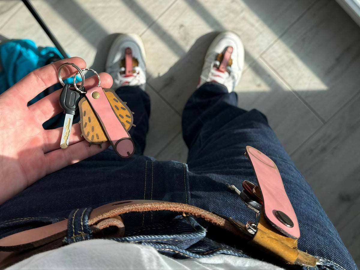 Hand holding a cheeky leather keychain with a belt carabiner, Lamamarka