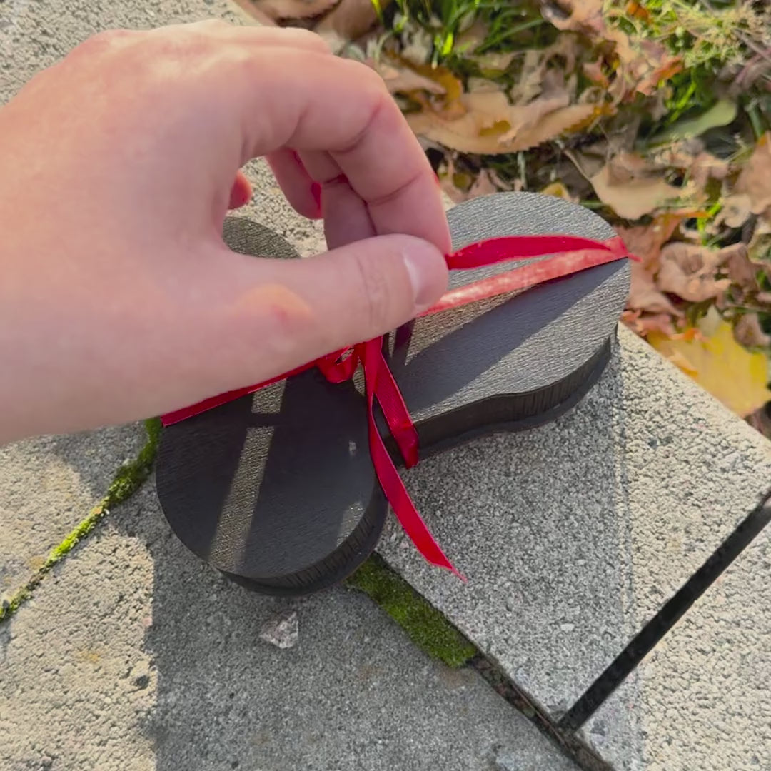 Red ribbon untied from The Package wooden gift box, lid opens to a clip