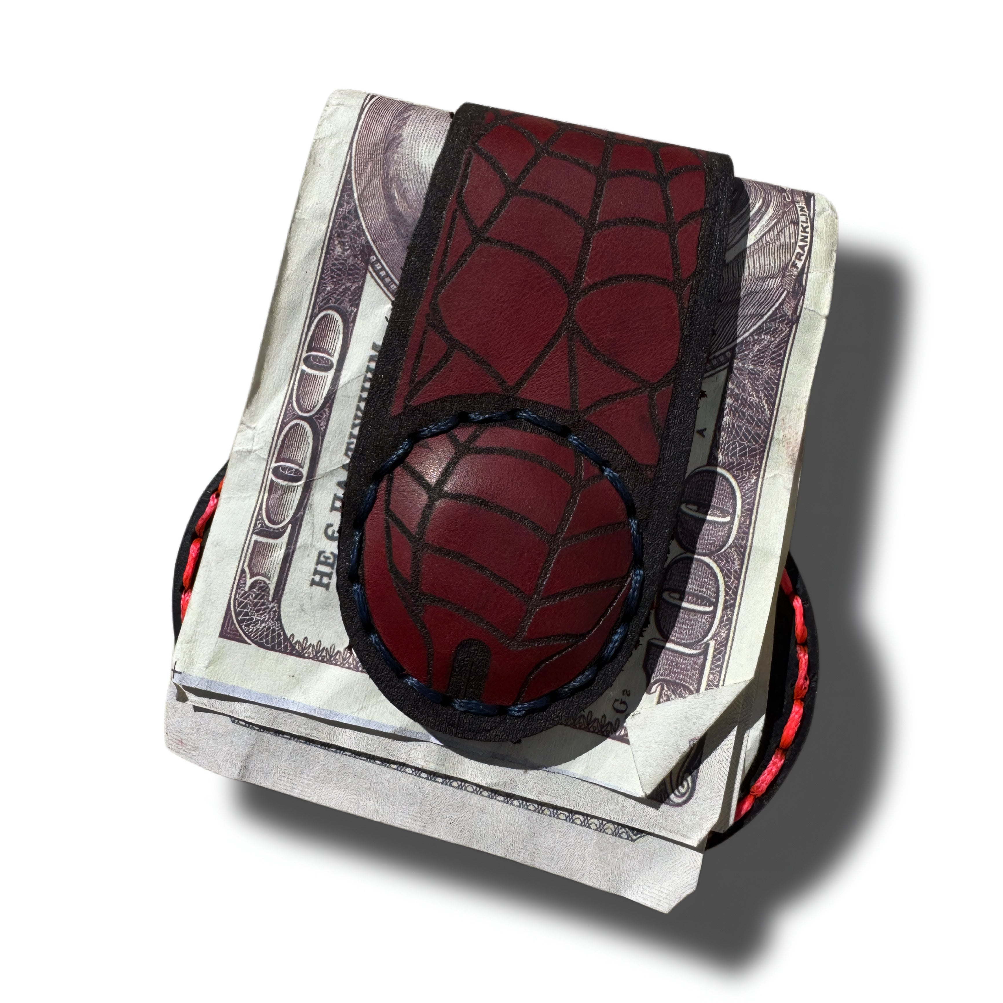 Spider web leather money clip, front view with red engraved web, holding folded cash - Lamamarka