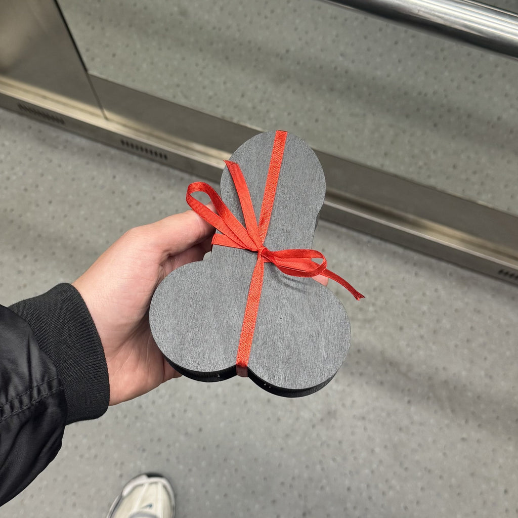 Shaped wooden gift box with red ribbon held in hand, ready to gift