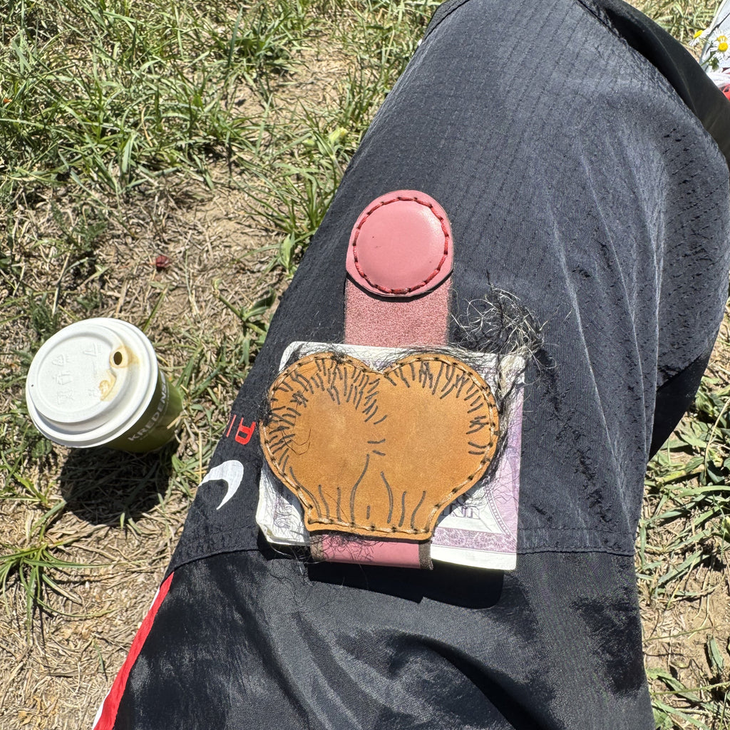 Brown leather XL cheeky money clip laid flat with cash, magnetic strap and hand stitching in view